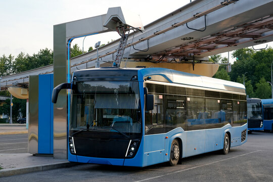 An electric bus at a charging station has its pantograph connected to a high-voltage connector at the final stop of the route.