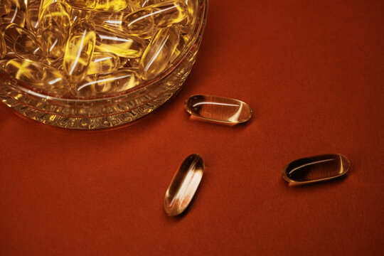 Omega 3 fish oil capsule in glass bowl on a red background