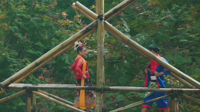 Traditional Dancers Crossing Rustic Bamboo Bridge in Forest
