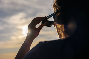 Person using solar eclipse glasses for safe total or annular solar observation, watching celestial event © Víctor Sánchez