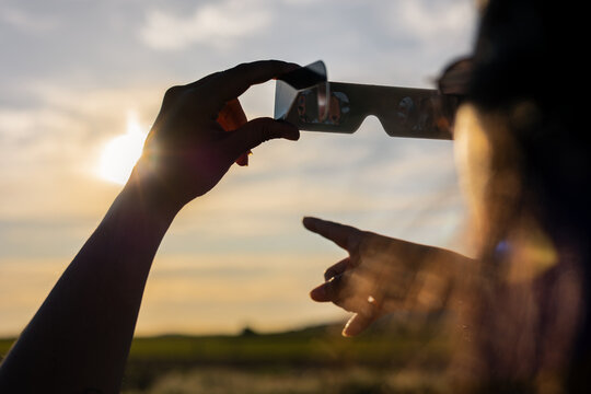Person observing astronomical event with cardboard solar eclipse glasses protecting eyes from bright sun