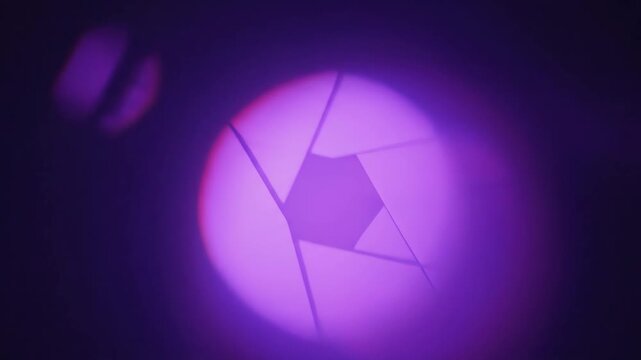 Close up view of a camera lens aperture iris with vibrant purple light flare effect and abstract bokeh background