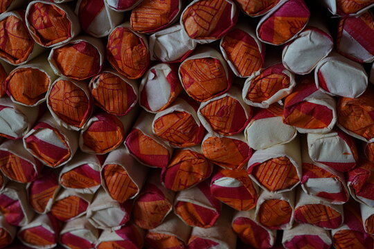 Traditional folded joss paper offerings arranged in a repetitive pattern for Chinese prayer rituals and cultural ceremonies. Close-up texture background with rich red and gold colors.