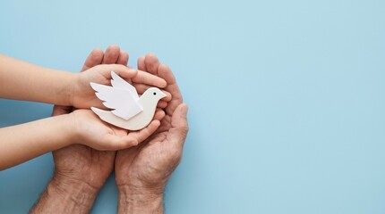 White paper dove in hands of adult and child, peace symbol for international day of non-violence, hope and harmony concept on blue background