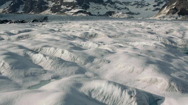 Aerial view flying over a massive glacier with meltwater pools and crevasses in Greenland