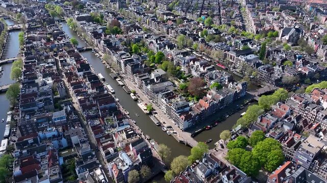Beautiful aerial drone view from above, Amsterdam,  Netherlands. Narrow canals with bridges, street, boats, architectures lines of houses, famous sights and traffic around city downtown in Holland.4K