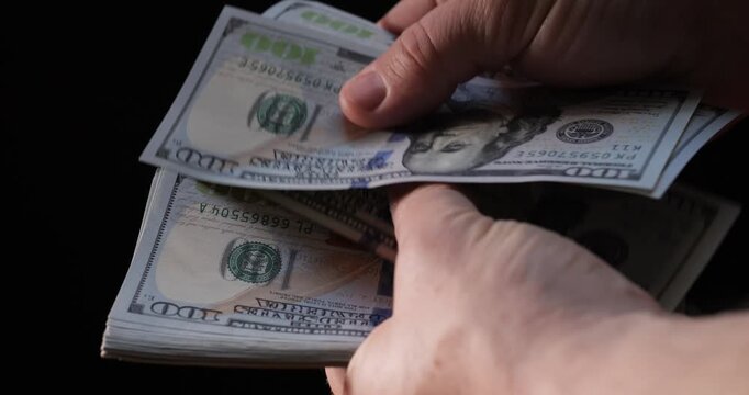 Count dollar bills by hand. 100 dollar bill in a bundle. Count money and income.