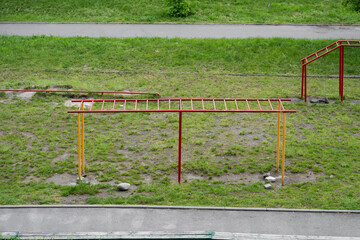 Fototapeta premium High-angle shot of outdoor metal monkey bars and sports equipment on a green grass field next to a walkway.