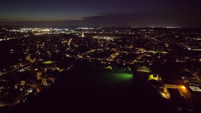 Aerial night view of Kettering Northamptonshire. neighborhood with glowing streetlights and a distant town skyline at dusk, conveying a quiet, peaceful evening atmosphere.