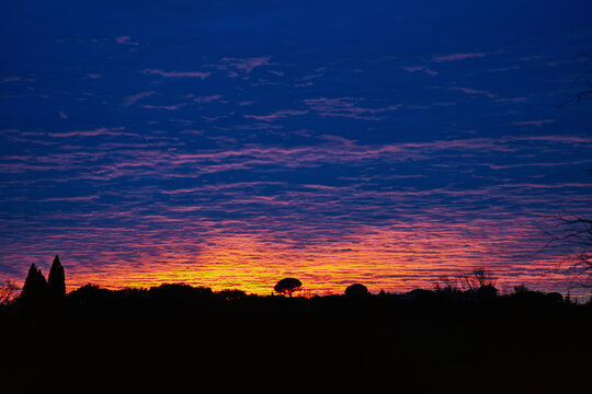 Ciel dramatique au crepuscule avec nuages colores en bleu violet et orange, silhouette de ville au coucher de soleil