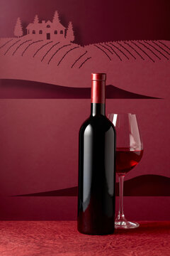 Bottle and glass of red wine on a red background.