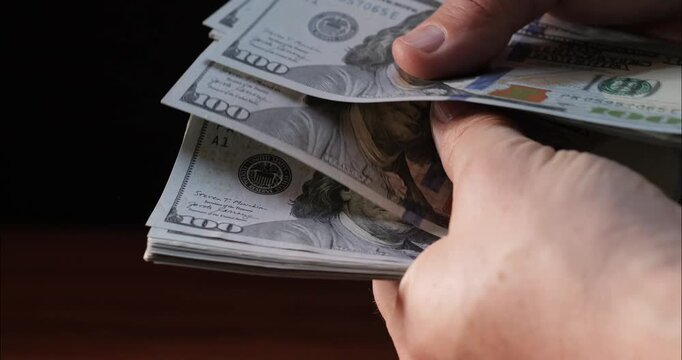 Count dollar bills by hand. 100 dollar bill in a bundle. Count money and income.