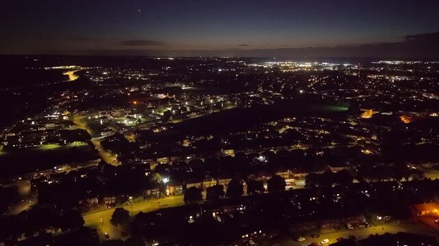 Aerial night view of Kettering Northamptonshire. neighborhood with glowing streetlights and a distant town skyline at dusk, conveying a quiet, peaceful evening atmosphere.