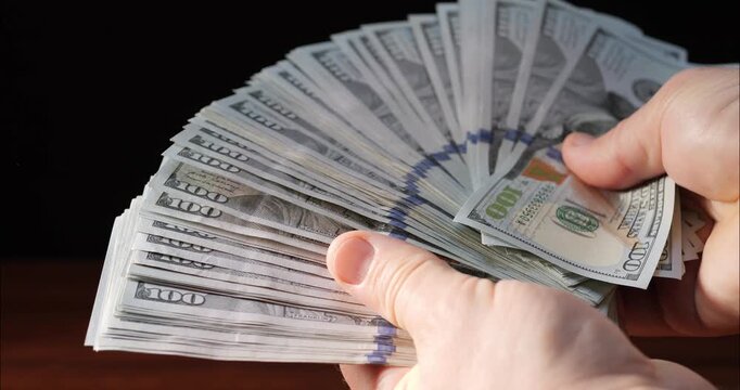 Count dollar bills by hand. 100 dollar bill in a bundle. Count money and income.
