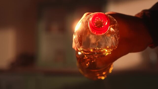 Close up of vegetable oil pouring from plastic bottle in warm kitchen light. Cooking ingredient concept with golden liquid stream, suitable for cooking at home, in a restaurant or cafe, healthy eating