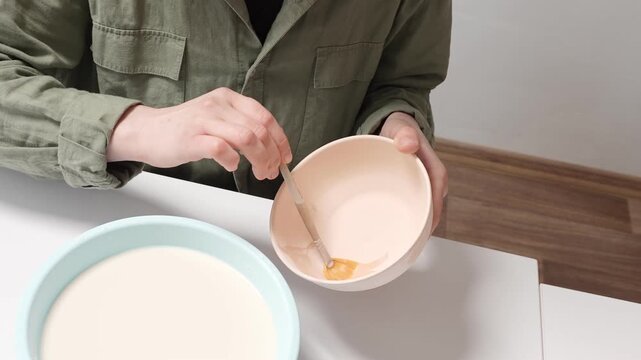 4K Video Slow Motion artist uses a wide studio paintbrush to apply thick glaze to a bisque ceramic bowl for an artistic finish. Artisan Glazing Ceramic Bowl with a Brush