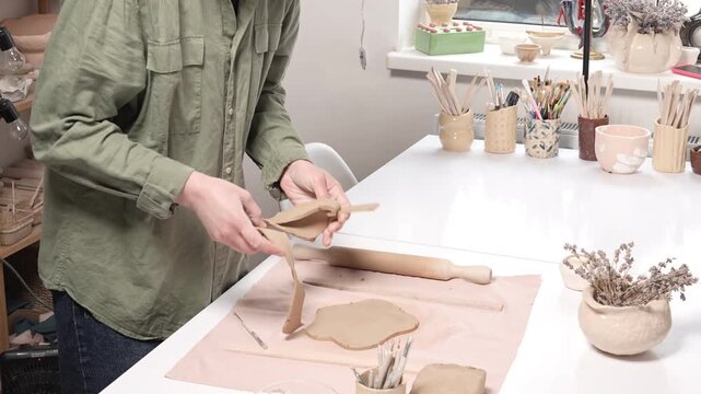 Artisan Cutting Clay Slab with Precision Cutter Tool 4k video in Slow motion. Artist uses sharp precision cutter tool to slice rolled raw clay, shaping piece of artwork