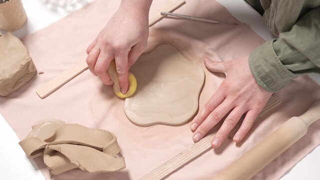 Artisan Refining Clay Edges with a Sponge 4k video slow motion. Close-up of pottery artwork refinement. Artisan hand gently wipes the border of an earthenware slab to remove imperfections