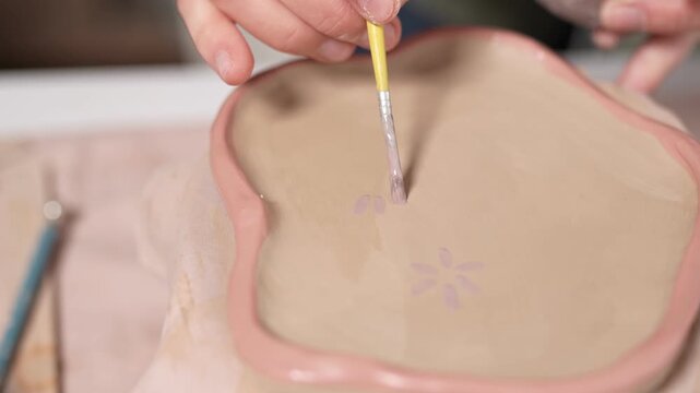 Artist paints a detailed botanical pattern for a 4k video slow motion ceramic artwork project. Artist Painting Flowers on Ceramic Plate 4K Video Slow Motion