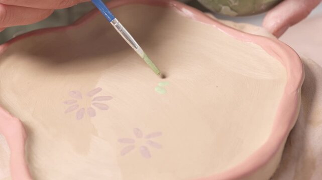 Artist paints a detailed botanical pattern for a 4k video slow motion ceramic artwork project. Artist Painting Flowers on Ceramic Plate 4K Video Slow Motion