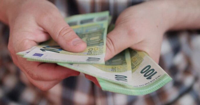 Counting money and income. Flipping through euro banknotes in a bundle with hands.