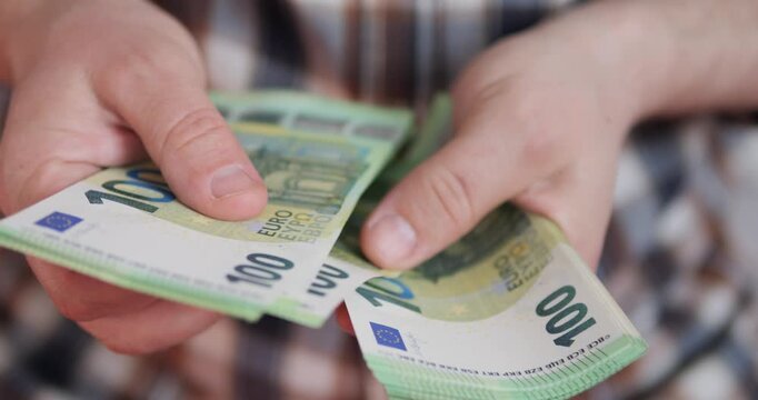 Counting money and income. Flipping through euro banknotes in a bundle with hands.
