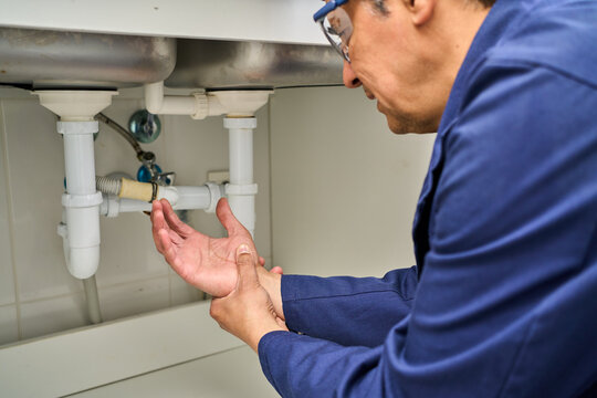 Plumber handyman with pain injury, work accident or sprain with agony. Contractor with muscle tension or carpal tunnel, inflammation. Plumber fixes sink for home improvement with pipes and tools.