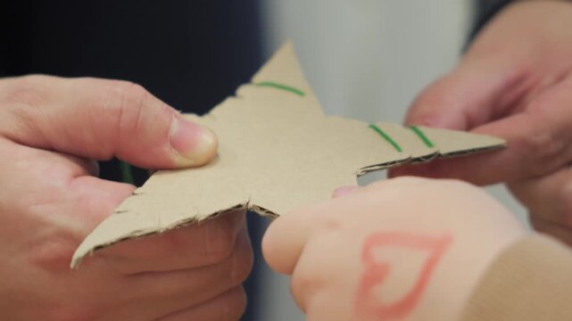 Handmade Cardboard Christmas Star Decoration with Red Thread and Wooden Beads During Holiday Crafting