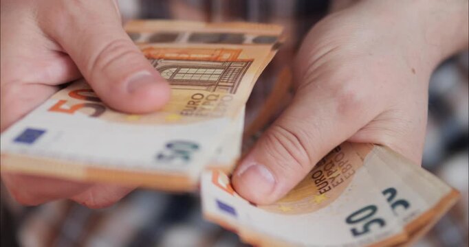 Counting money and income. Flipping through euro banknotes in a bundle with hands.