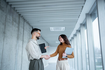 Business partners shaking hands making agreement in office hallway © Migma_Agency