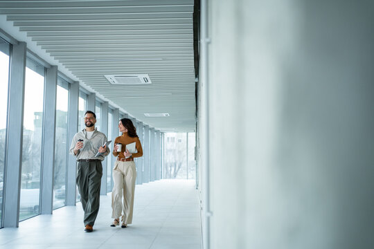 Business coworkers walking in modern office hallway discussing work