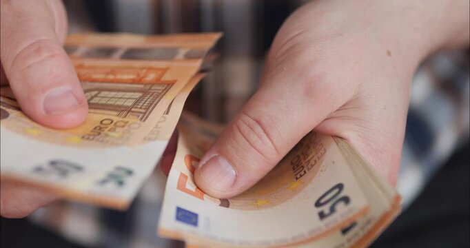 Counting money and income. Flipping through euro banknotes in a bundle with hands.
