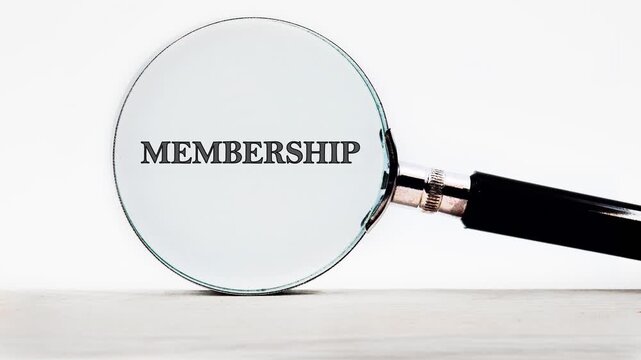 Magnifying glass on a white surface clarifies distorted letters. The word membership becomes perfectly clear and readable