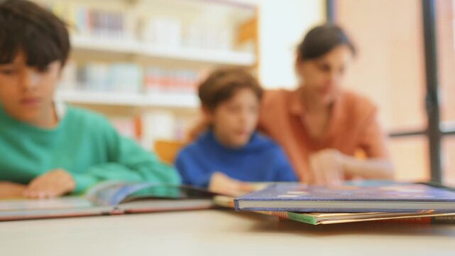 Teacher or librarian helping elementary school children with reading in a public library, promoting literacy and education through group study and learning activities