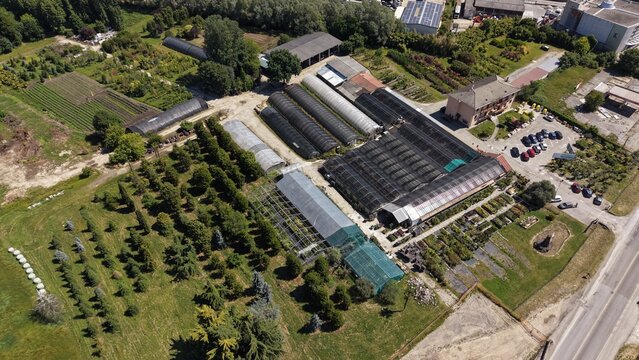 Drone aerial footage of a large plant nursery with greenhouses, tree rows and ornamental plants in the Lombardy countryside of Northern Italy.