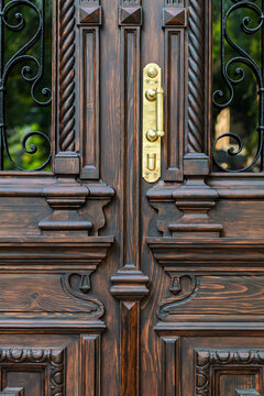 Brass door handle on carved wooden entrance, restored historic door detail, Odesa Ukraine