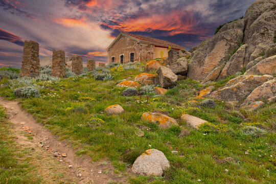Ruins of an old building on a rocky hill with a dramatic sunset, Capo Testa, Sardinia Island, Italy