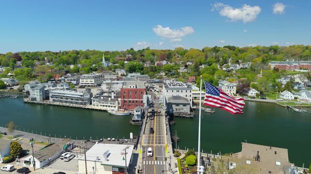 Mystic River Bascule Bridge aerial view, a high-angle drone video showing cars crossing the iconic drawbridge near downtown storefronts and the waterfront on a bright spring day in Mystic Connecticut.