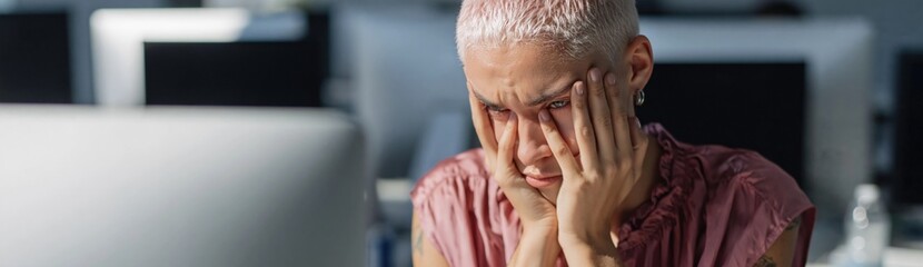 Fototapeta premium Young adult frustrated and covering face at office desk