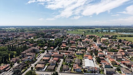 Obraz premium Aerial View of a Quaint Town: An aerial perspective reveals a charming European town with red-tiled roofs, nestled amongst green fields and trees, Pantigliate, Lombardy, Italy,
