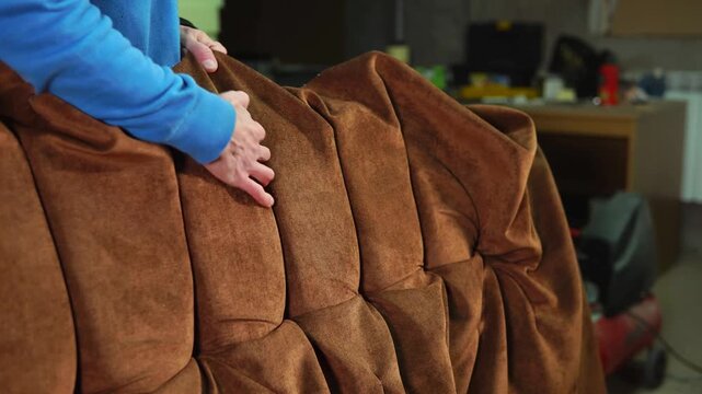 Upholsterer Repairing Brown Tufted Sofa in Workshop