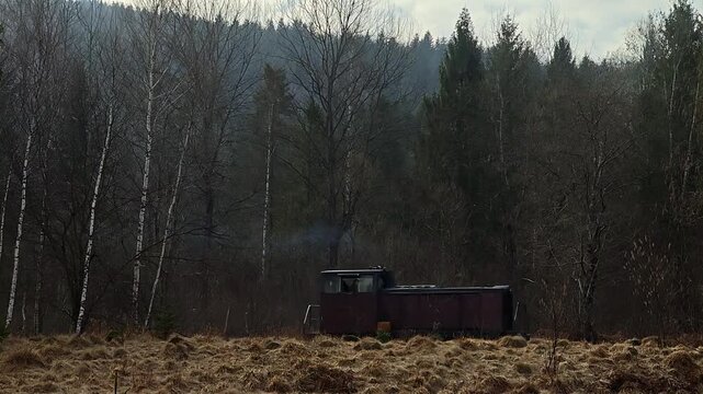 Industrial narrow-gauge locomotive moving with empty flatbed wagons