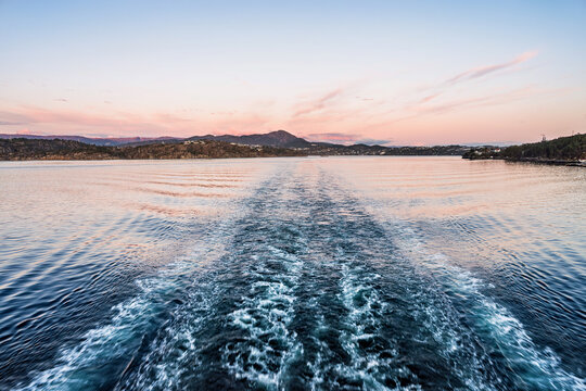 View from the stern of a ship toward the horizon in the evening light.