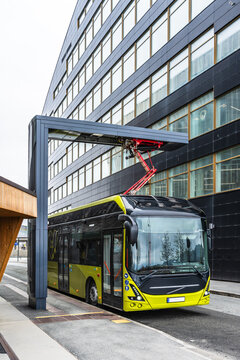 An electric city bus is charging at a charging station in Trondheim, Norway. Vertical.