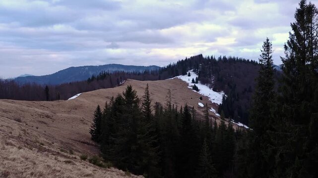 Mountain slope with patches of snow under cloudy sky