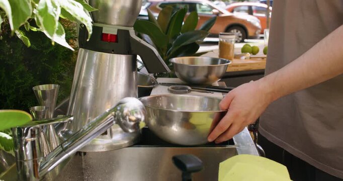 Summer drink preparing. Automated ice crushing. Unrecognizable experienced chef man hands using electric machine for cool citrus fresh outside.