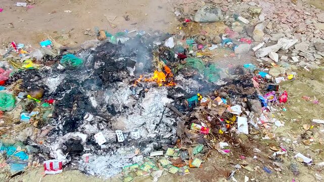 Burning garbage and smoke causing environmental pollution in Bangladesh urban waste dumping area during daytime conditions
