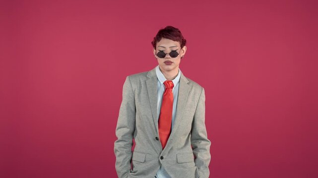 Androgynous person in suit and sunglasses posing