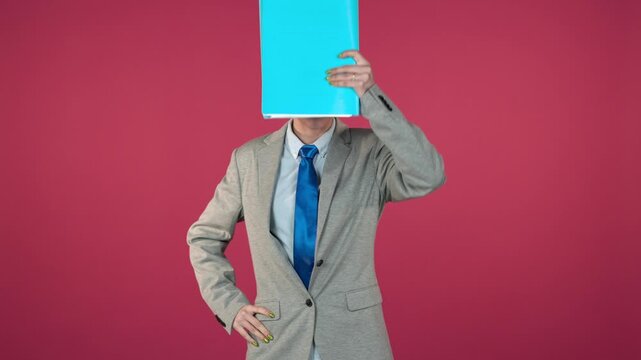Playful businesswoman hiding behind a blue folder on red background