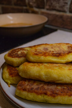 Frying potato zrazy with cabbage filling in a pan on an induction stove. Crispy golden fried patties served on a plate, showcasing the final step of cooking traditional Eastern European rustic comfort